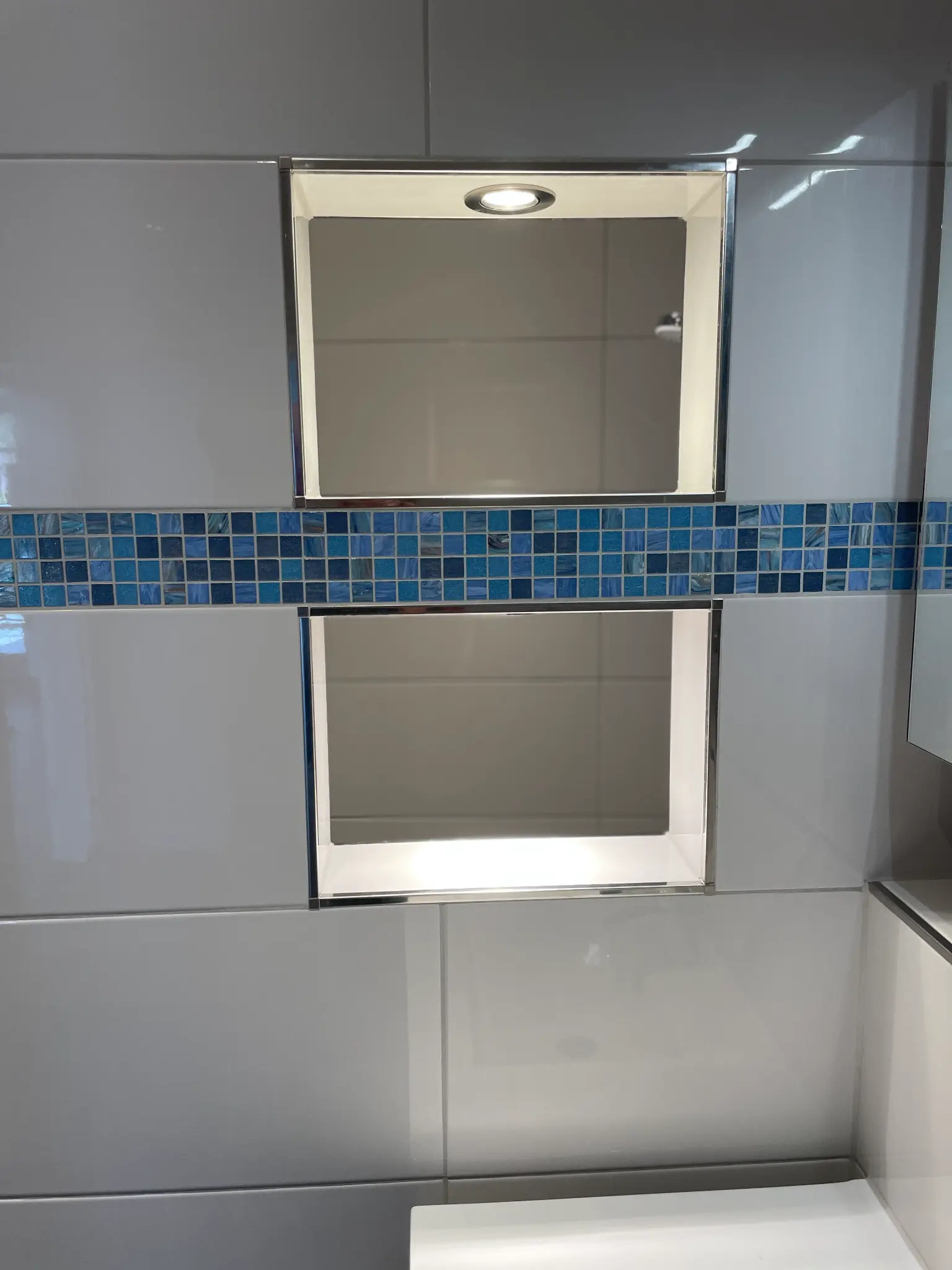 Beleuchtete Wandnischen mit türkis-blauem Mosaik - Badsanierung Winterhude